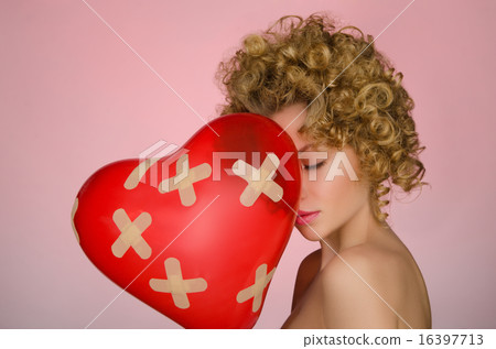 Unhappy young woman with ball in shape of heart 16397713