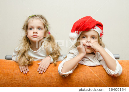 Two girls looking to left leaning back on the couch 16409164