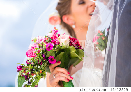 Bridal pair kissing under veil at wedding 16412809