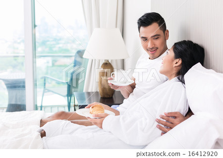 Asian couple lounging in bed at morning 16412920