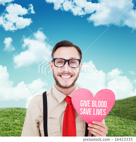 Composite image of geeky hipster smiling and holding heart card 16423335