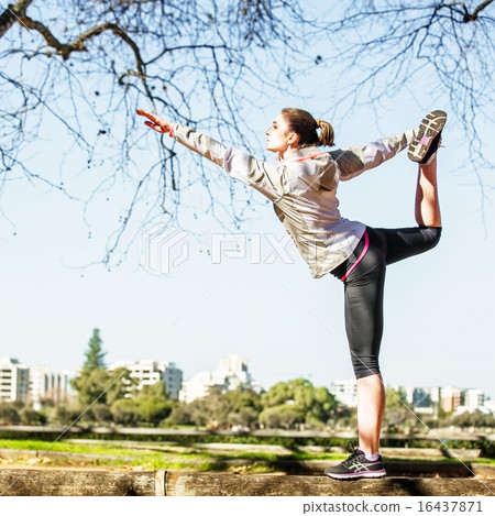 Young woman stretching out on bench before jogging in autumn nature with city at background Young woman stretching out on bench before jogging in autumn nature with city at background 16437871