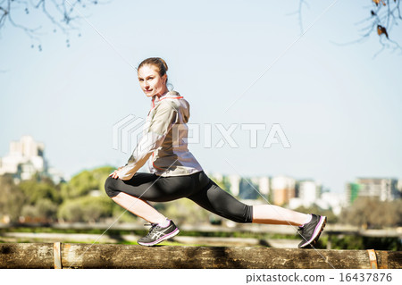 Young fit girl stretching out on bench before exercising in autumn pak with city at background Young fit girl stretching out on bench before exercising in autumn pak with city at background 16437876