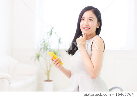 看智能手機的婦女在屋子裡 看智能手機的婦女在屋子裡 16465764