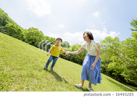 My son and mother playing in the lawn squares in the park 16493285