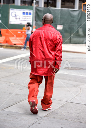 Red dressed black man walking in Harlem on weekday 16505630