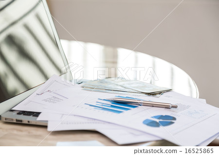 Financial charts on the table with laptop 16525865