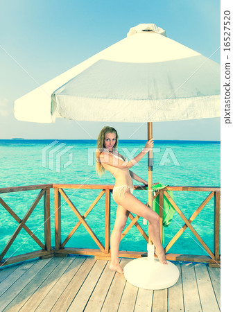 Young woman tans on a water villa terrace , Maldiv Young woman tans on a water villa terrace , Maldiv 16527520