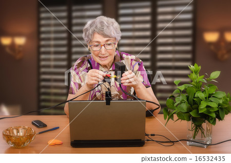 Retired woman is sitting at desk with AV adapter 16532435