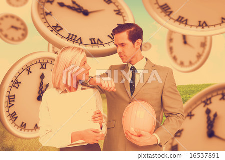 Composite image of architects with plans and hard hat looking at 16537891