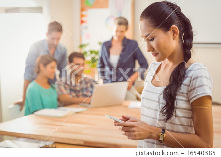 Businesswoman using her phone in the office 16540385