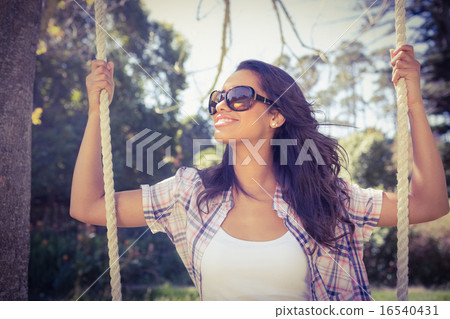 Pretty brunette swinging in park Pretty brunette swinging in park 16540431