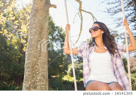 Pretty brunette swinging in park 16541305