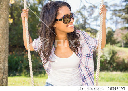 Pretty brunette swinging in park 16542495