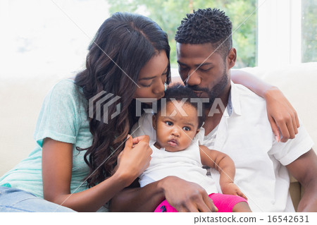 Happy couple with their baby girl on couch Happy couple with their baby girl on couch 16542631
