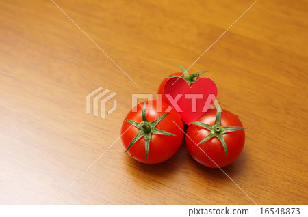 Strong heart contrast with three fresh mini tomatoes on the table 16548873