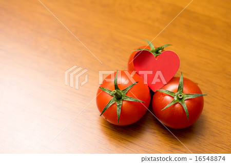 Strong heart contrast with three fresh mini tomatoes on the table 16548874
