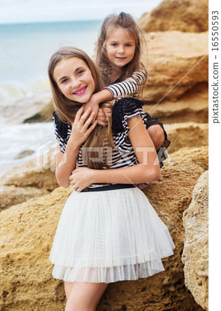 Portrait of two friends girls sitting on the beach 16550593