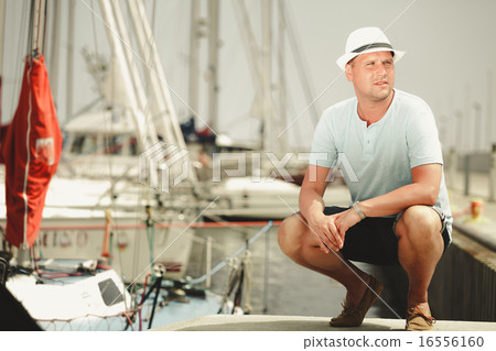 Handsome fashion man on pier in port with yachts. 16556160