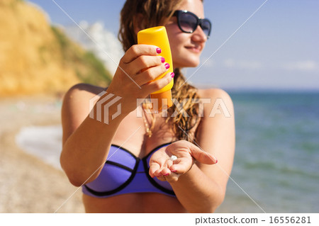 Woman is holding yellow tube with sunscreen tan lotion  16556281