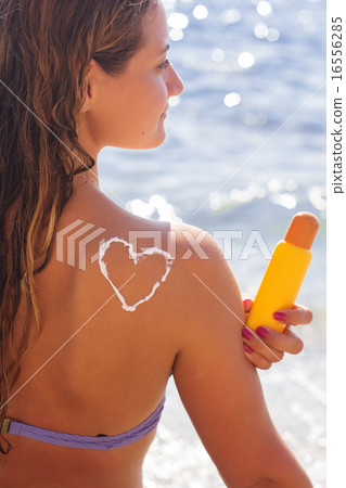 Woman is holding yellow tube with sunscreen tan lotion Woman is holding yellow tube with sunscreen tan lotion 16556285