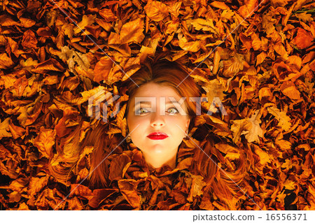 Portrait of young woman in autumn leaves. 16556371