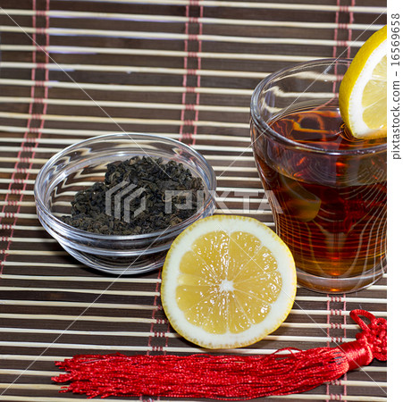 tea with part of a lemon near a glass with tea, a subject drinks tea with part of a lemon near a glass with tea, a subject drinks 16569658