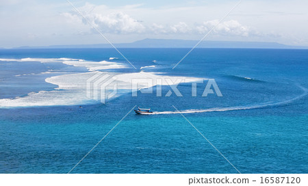 Clear blue ocean with boat and surfers on waves 16587120