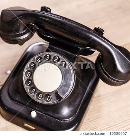 Old black phone with dust and scratches on  floor 16589907