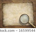 old parchment or map on wooden desk with magnifying glass 16599544