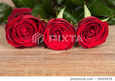 圖庫照片: three red roses on wood