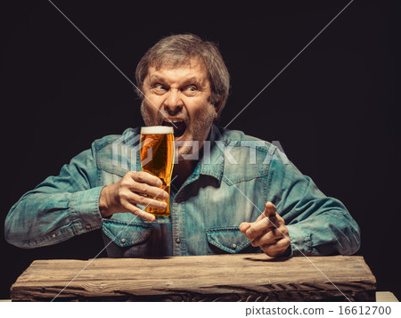 The screaming man in denim shirt with glass of beer 16612700