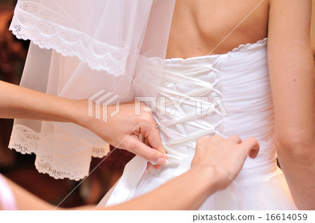 bridesmaid tying bow on wedding dress 16614059