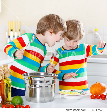 Two little kid boys eating spaghetti in domestic kitchen. 16617576