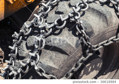 Snow chain over huge tractor wheel, closeup Snow chain over huge tractor wheel, closeup 16618984