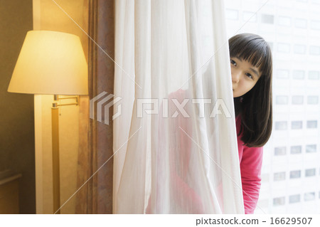 A girl who takes a face from the back of the curtain A girl who takes a face from the back of the curtain 16629507