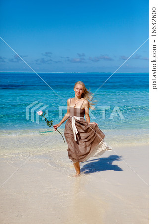 beautiful woman with a rose runs on the edge of th 16632600