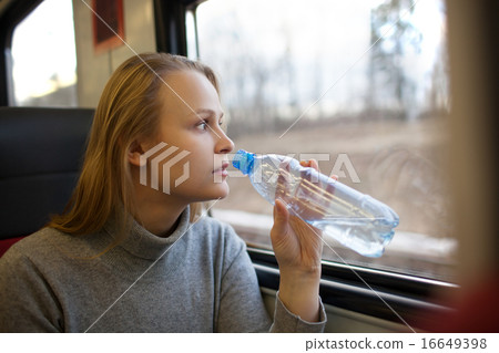 Woman drinking water and looking out train window Woman drinking water and looking out train window 16649398