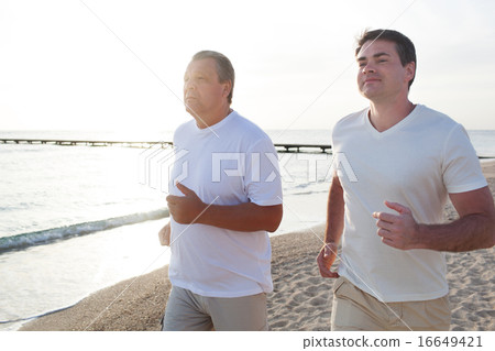 Two men running along the coast in bright sunlight 16649421