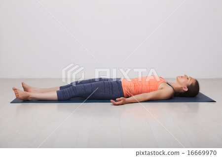 Beautiful sporty fit yogi girl relaxes in yoga asana Savasana 16669970