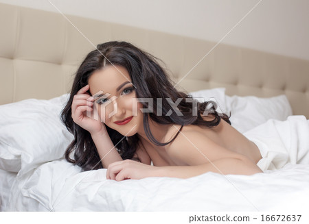 Sexy brunette smiling at camera while lying in bed Sexy brunette smiling at camera while lying in bed 16672637