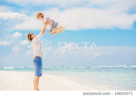 Young happy father playing with his little son standing barefoot at the beach against ocean and Young happy father playing with his little son standing barefoot at the beach against ocean and 16683071