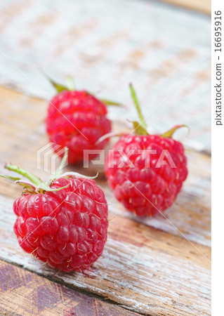 Three red raspberry on old vintage wooden table. Three red raspberry on old vintage wooden table. 16695916