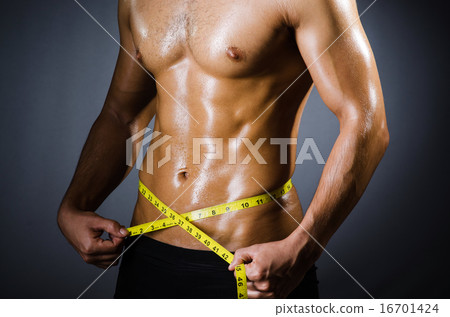 Muscular man measuring his muscles Muscular man measuring his muscles 16701424