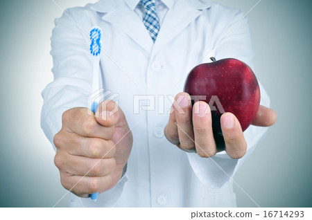 a dentist showing a toothbrush and an apple 16714293