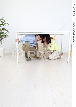 A couple evacuating under the table due to an earthquake A couple evacuating under the table due to an earthquake 16716217