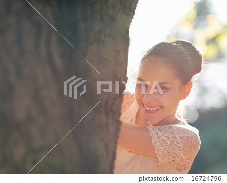 Happy girl looking out from tree Happy girl looking out from tree 16724796