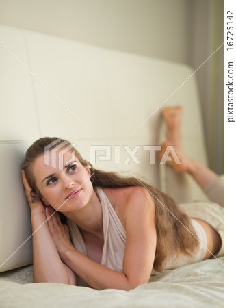 Thoughtful young woman laying on sofa Thoughtful young woman laying on sofa 16725142