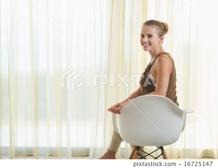Happy young woman sitting on modern chair Happy young woman sitting on modern chair 16725147