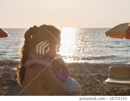 Silhouette of mother hugging baby on lonely beach Silhouette of mother hugging baby on lonely beach 16725153